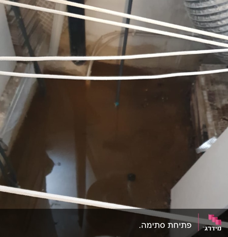 דליפת מים בחדר עם צינור שחור ודלי